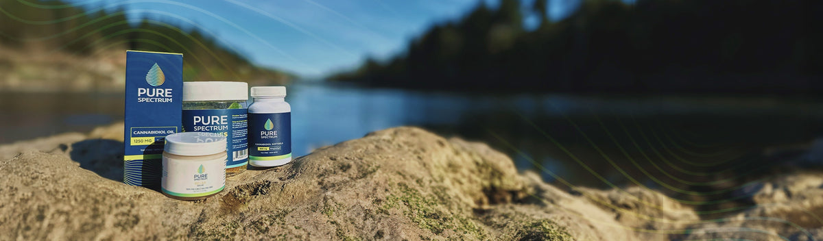 Pure Spectrum CBD products on a rock by a mountain lake