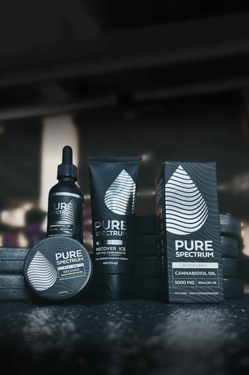 Pure Spectrum Black Label CBD products including oil, cream, and balm with gym background